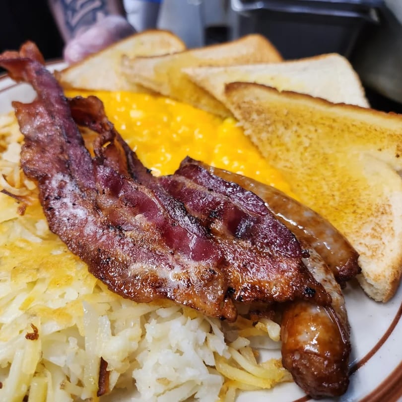Cislo's Family Restaurant breakfast plate with crispy bacon, sausage, hash browns, scrambled eggs, and toast.